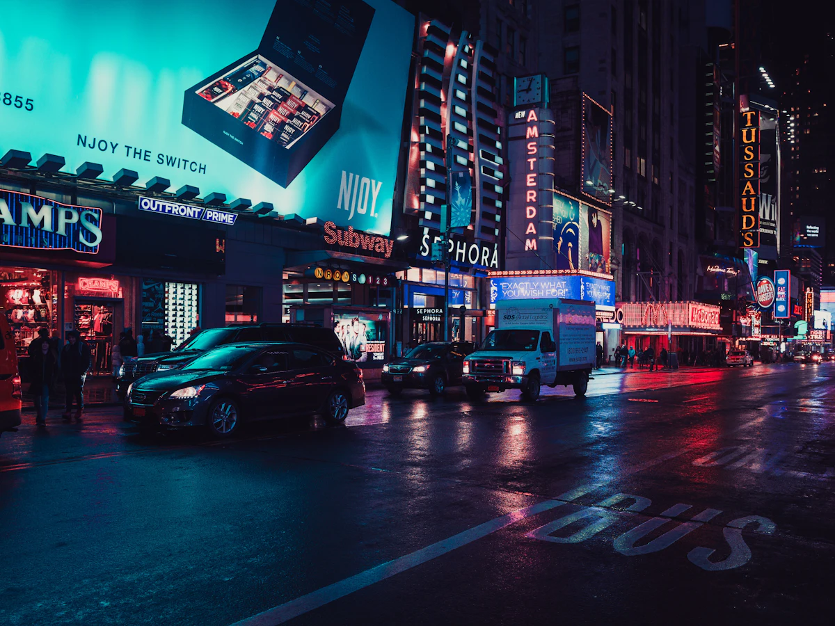 Neon-lit city street at night with a car passing through