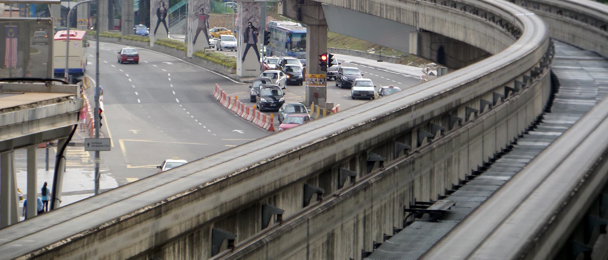 Elevated monorail guideway curving above a busy city road